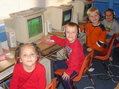 Children wearing headphones at computers in a classroom