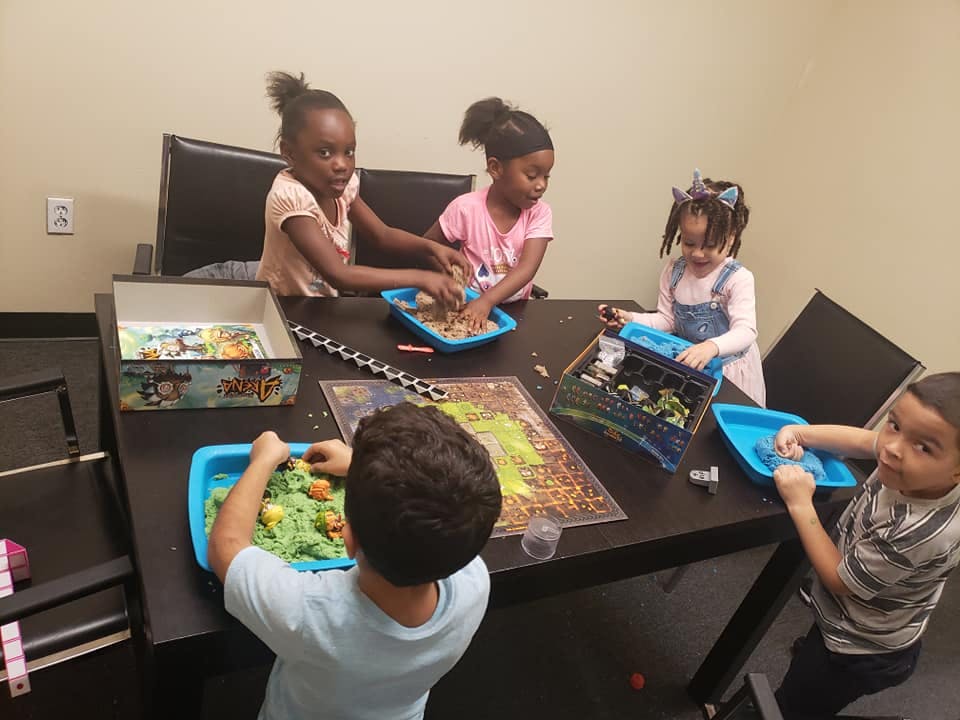 Four children playing with sensory bins at a table