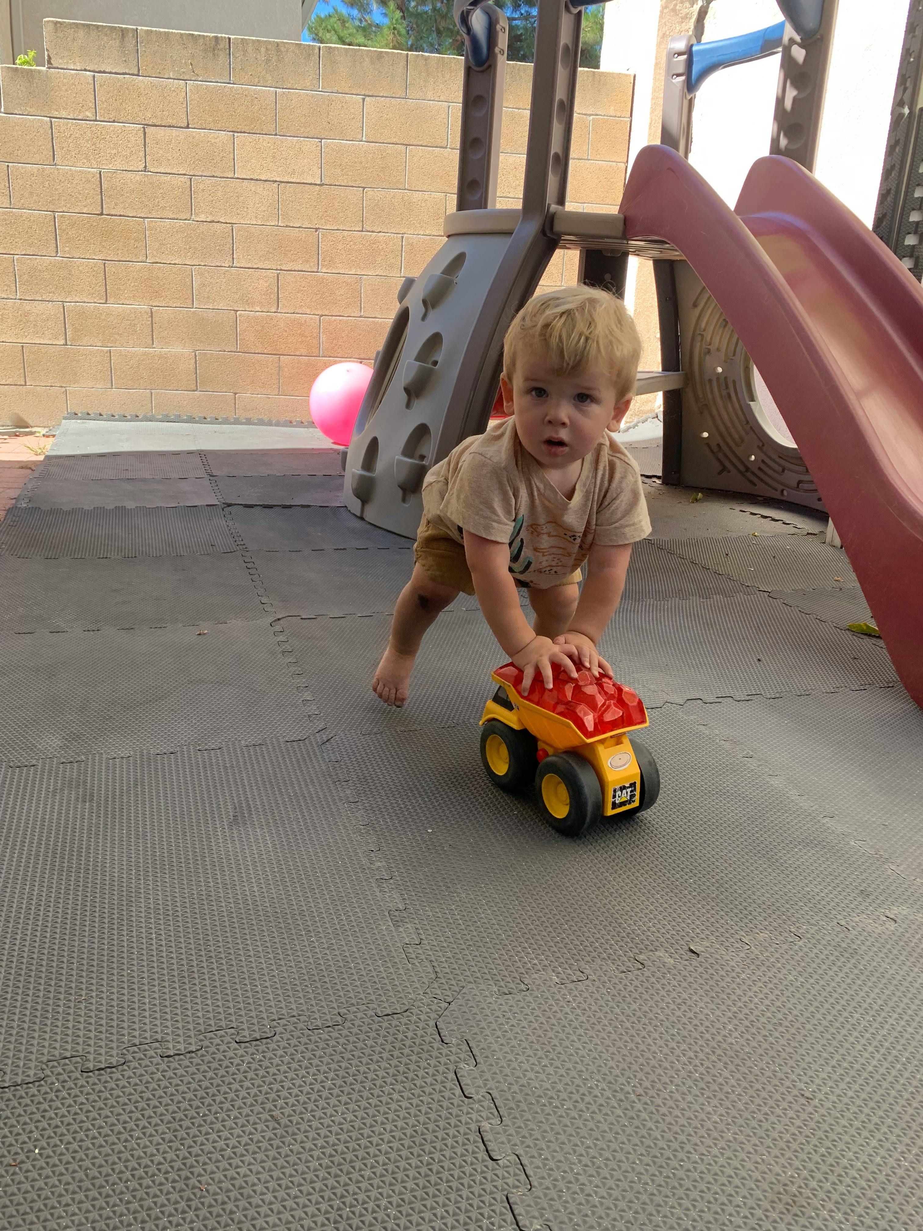 Child looking at camera while holding a toy dump truck