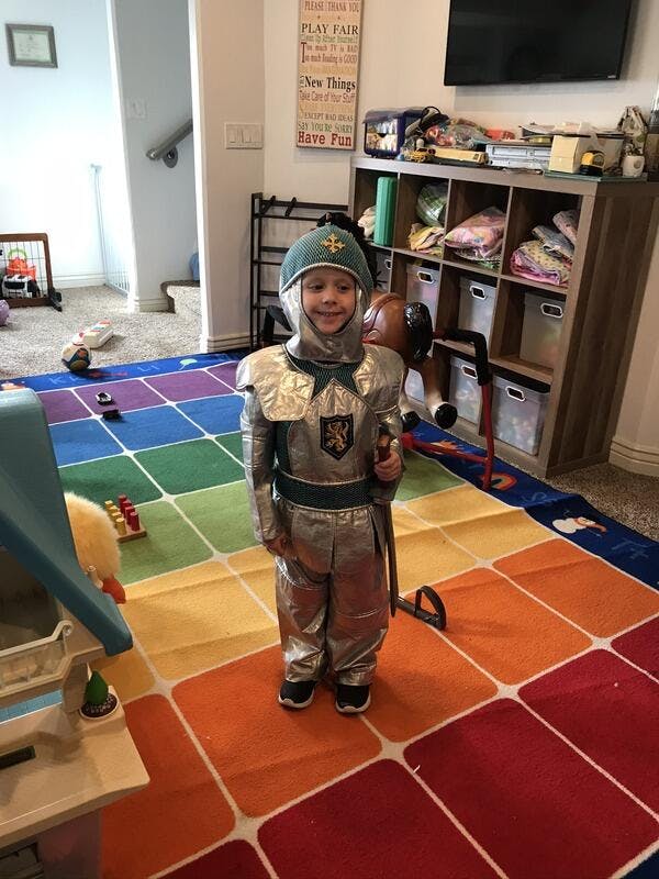 Child in a knight costume holding a toy sword