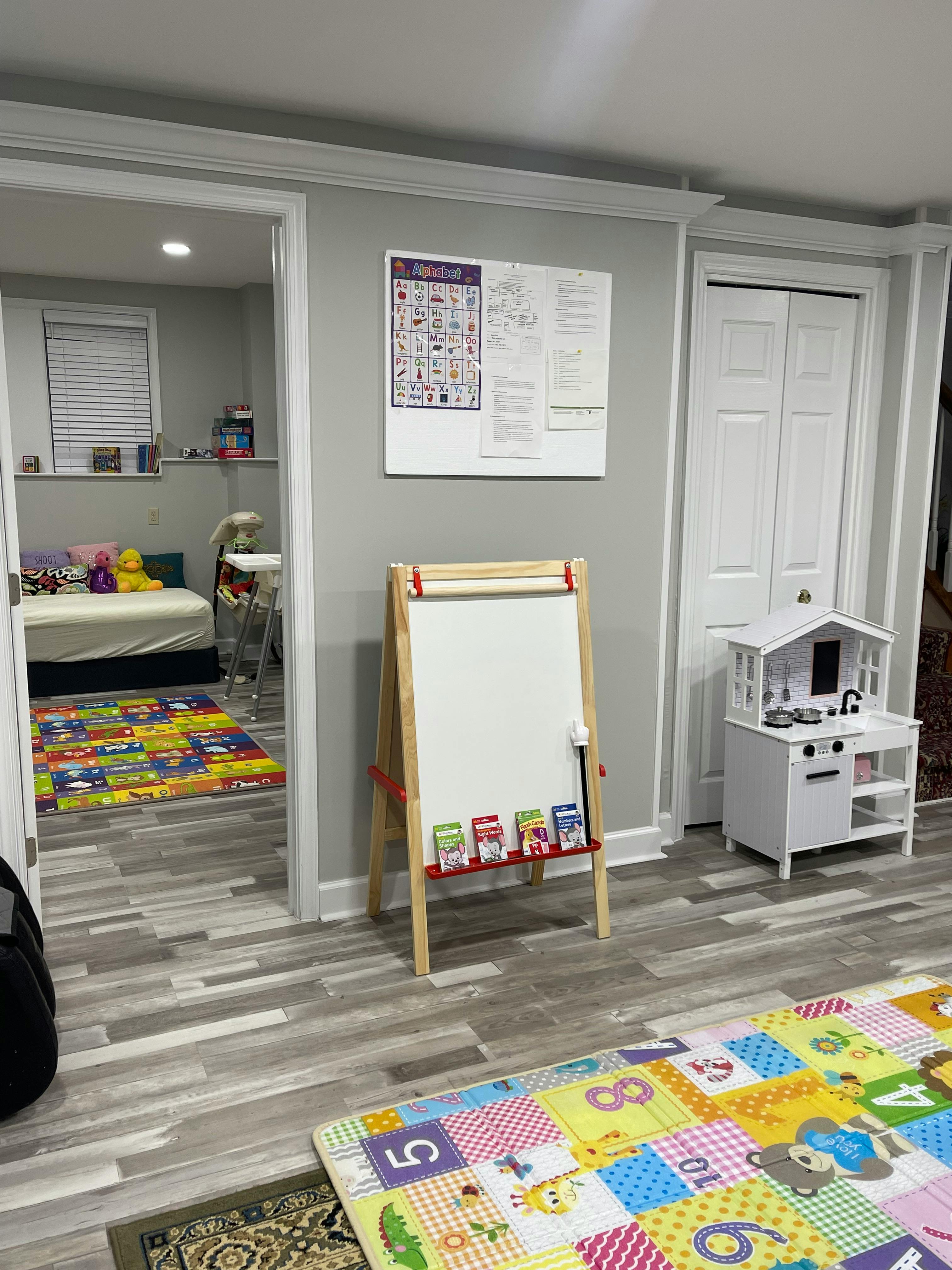 Playroom with an easel, toy kitchen, and colorful playmats