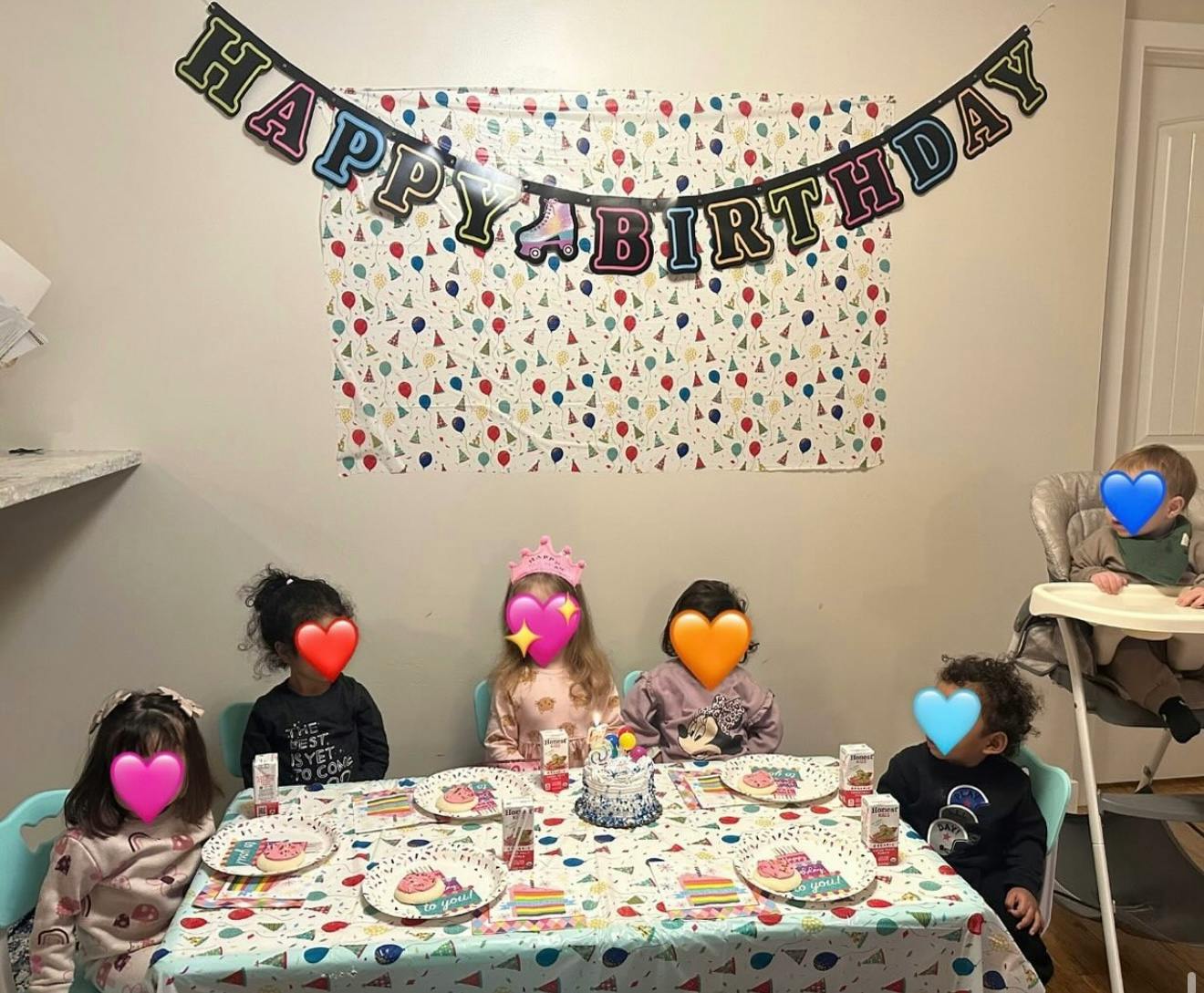 Children sitting at a table with a birthday banner above them