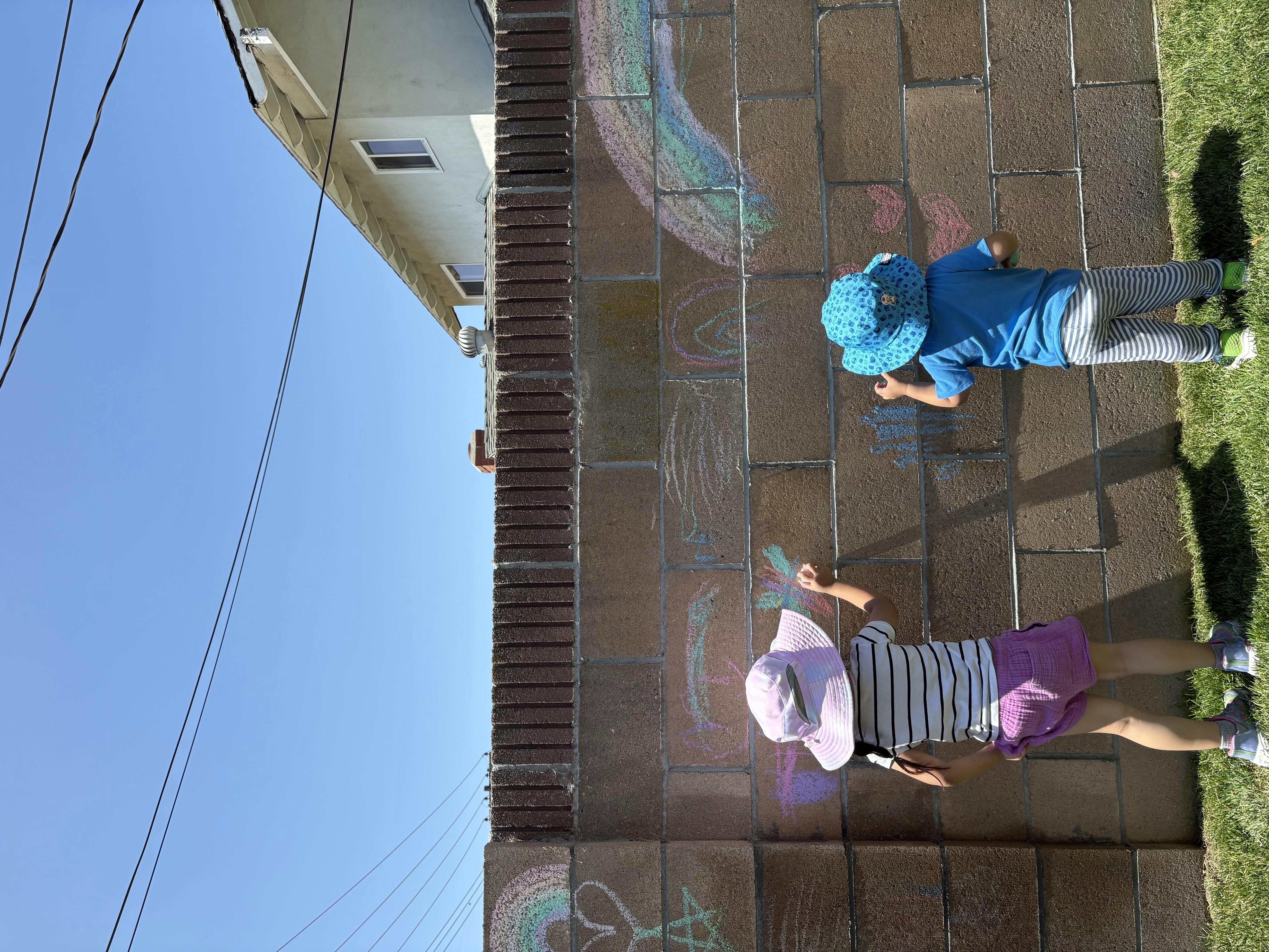Two children drawing with chalk on a wall