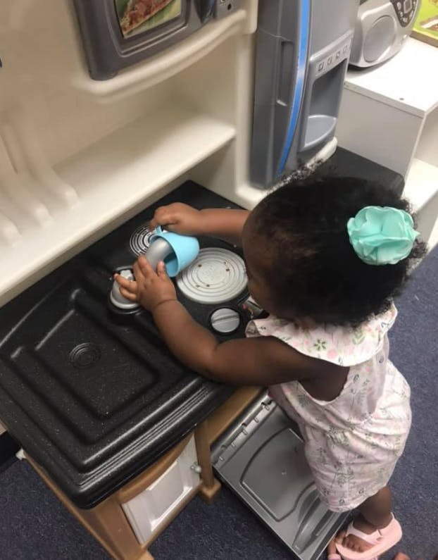 Child playing with a toy stove in a play kitchen