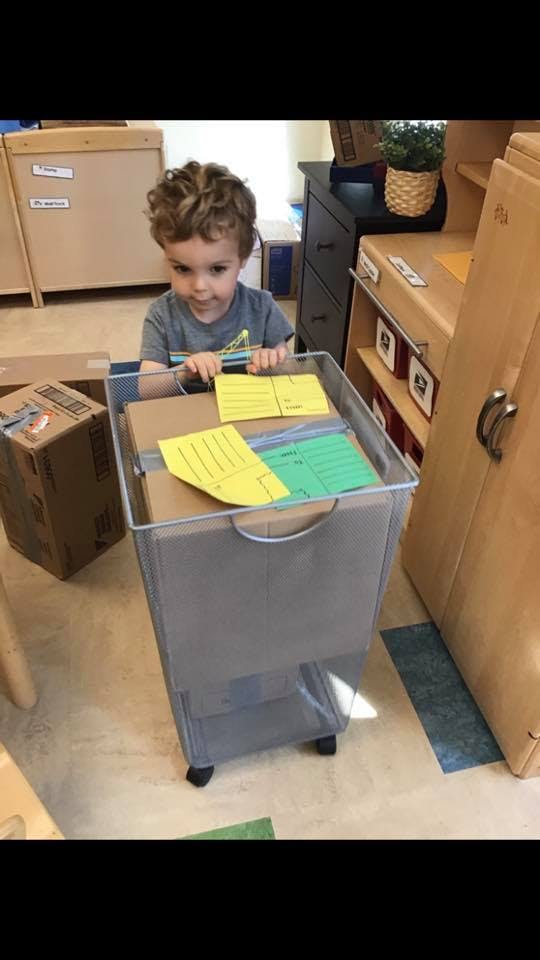 Child looking into a rolling bin with papers