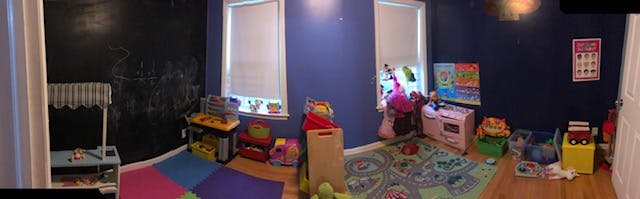Playroom with blue and black walls, toys, and colorful floor mats