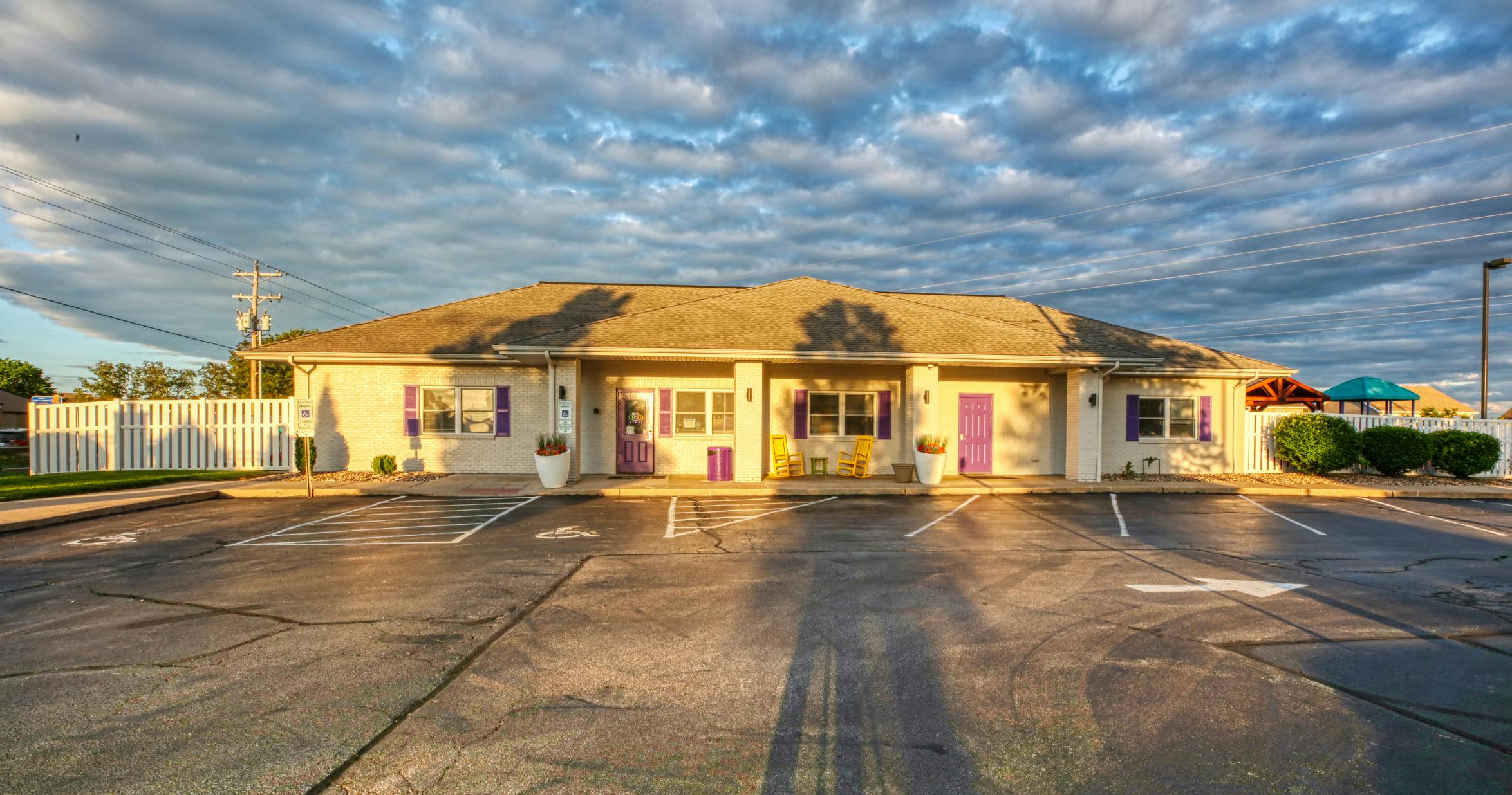 Building with purple doors and yellow chairs in front, playground in the background