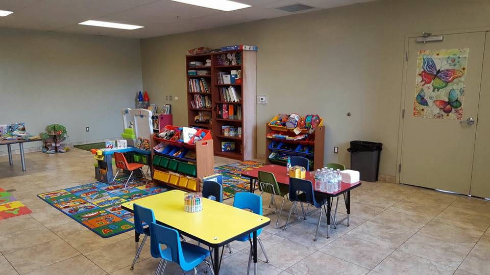 Classroom with small tables and chairs, bookshelves, and a colorful rug
