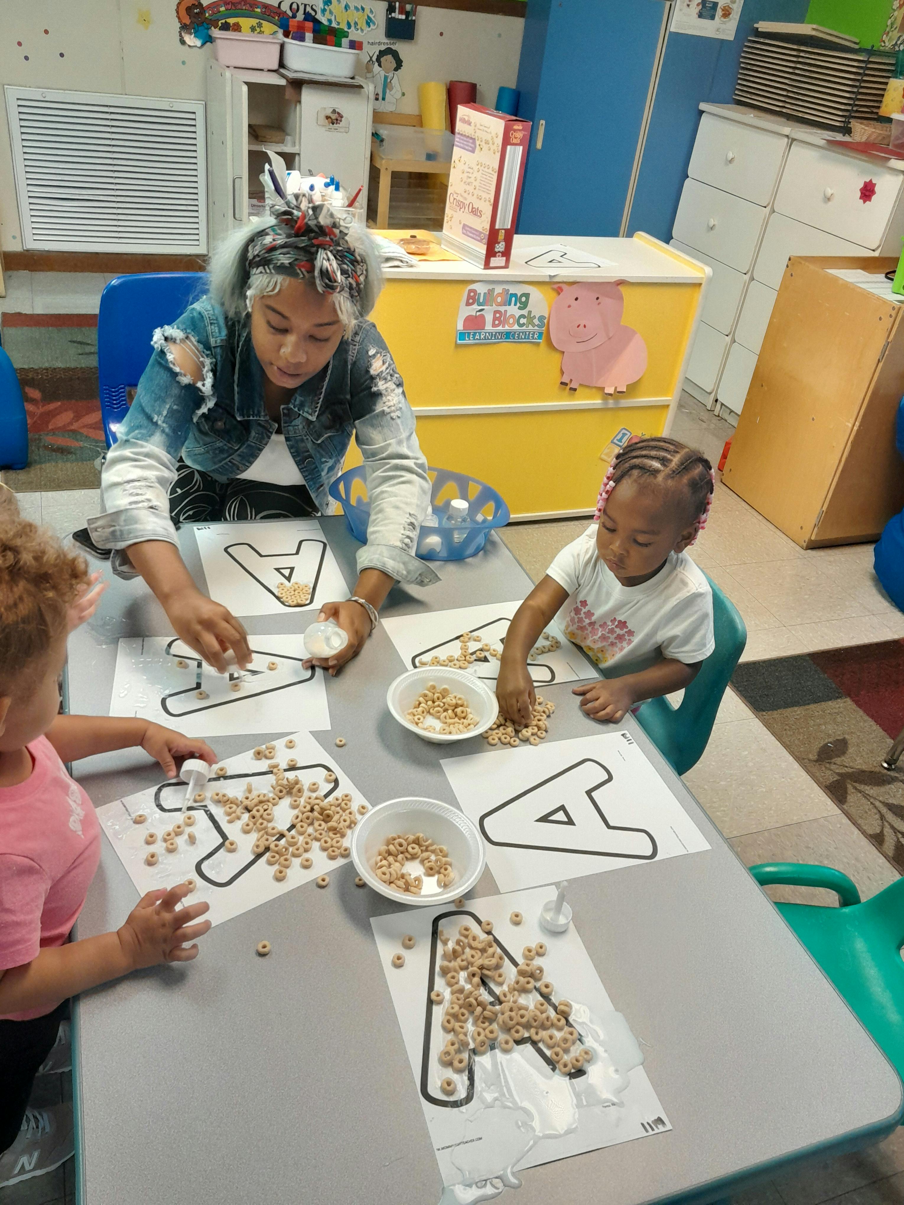Adult and two children doing an alphabet craft with cereal