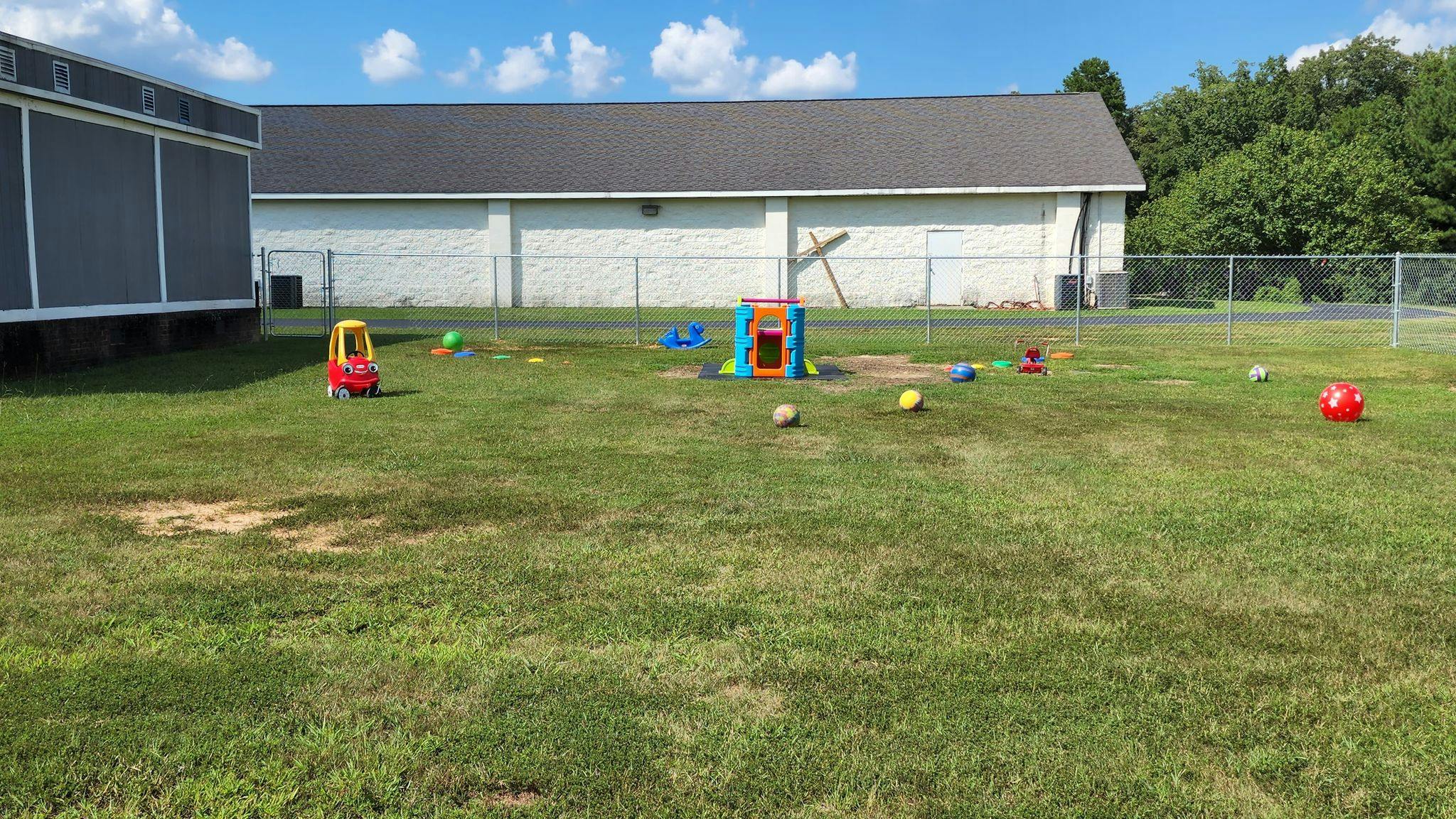 Outdoor play area with toys and balls on grass