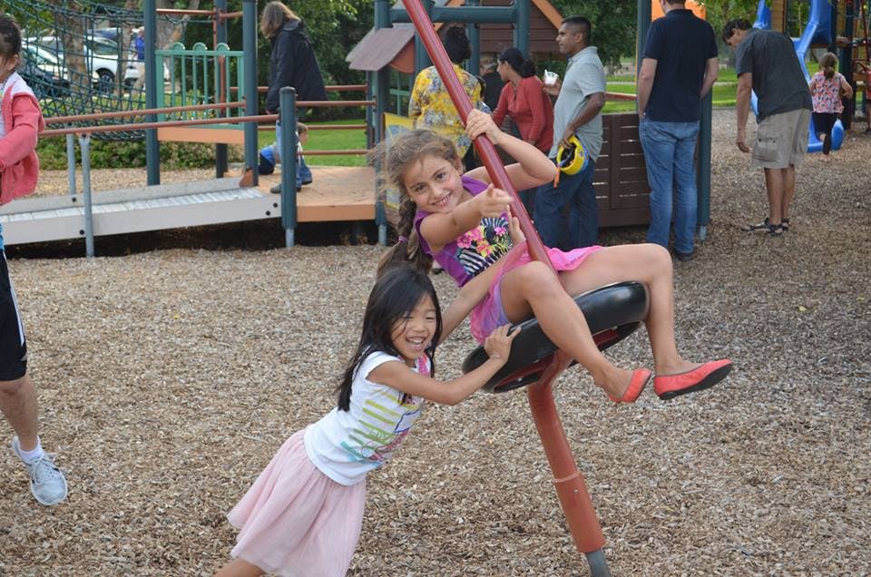 Two children playing on a spinning playground ride