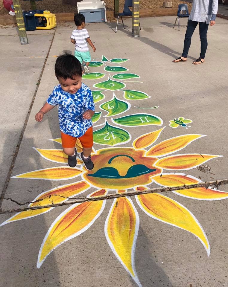 Child walking on a painted sunflower and leaves on the ground