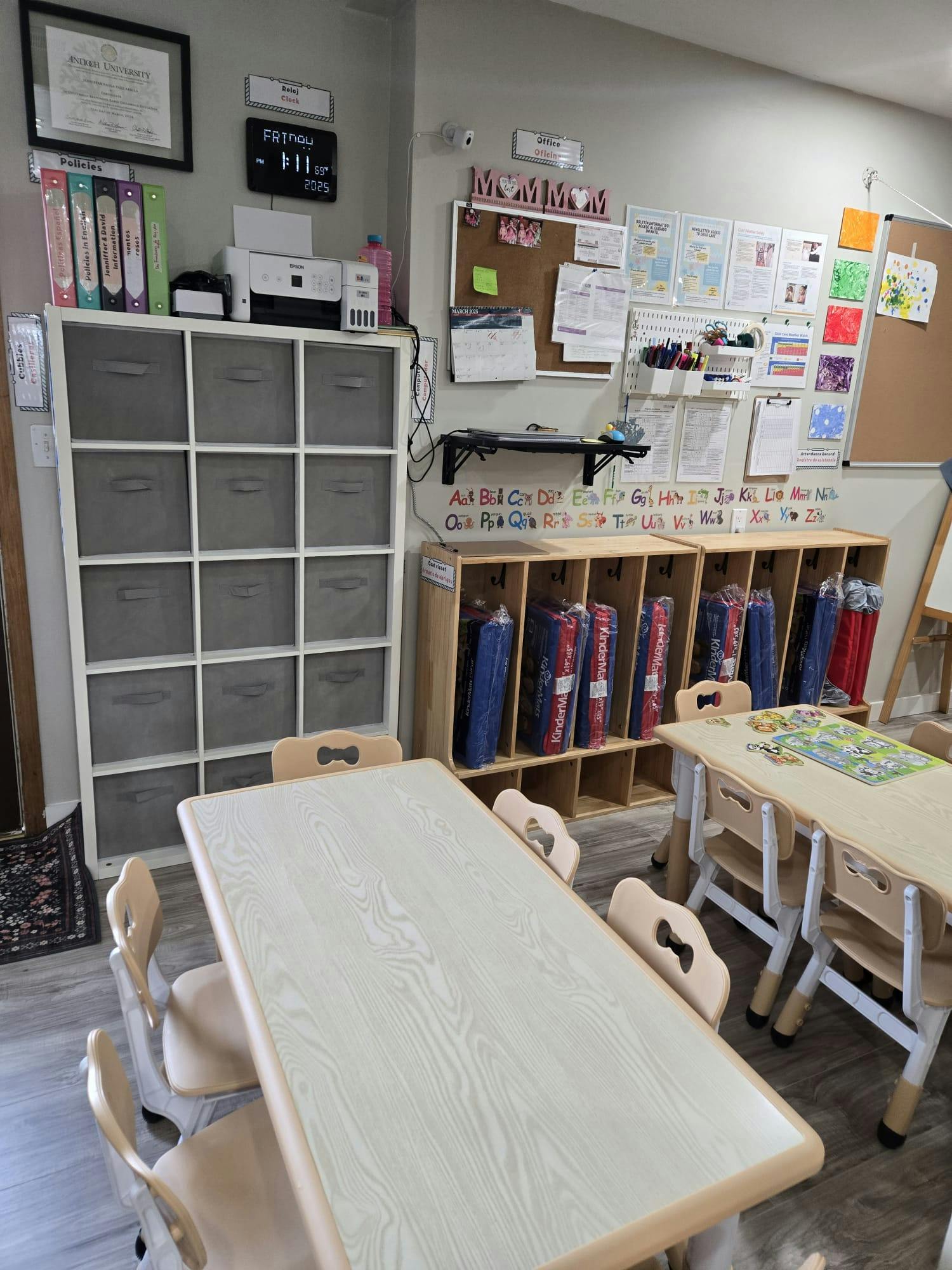 Classroom with tables, chairs, storage shelves, and bulletin boards