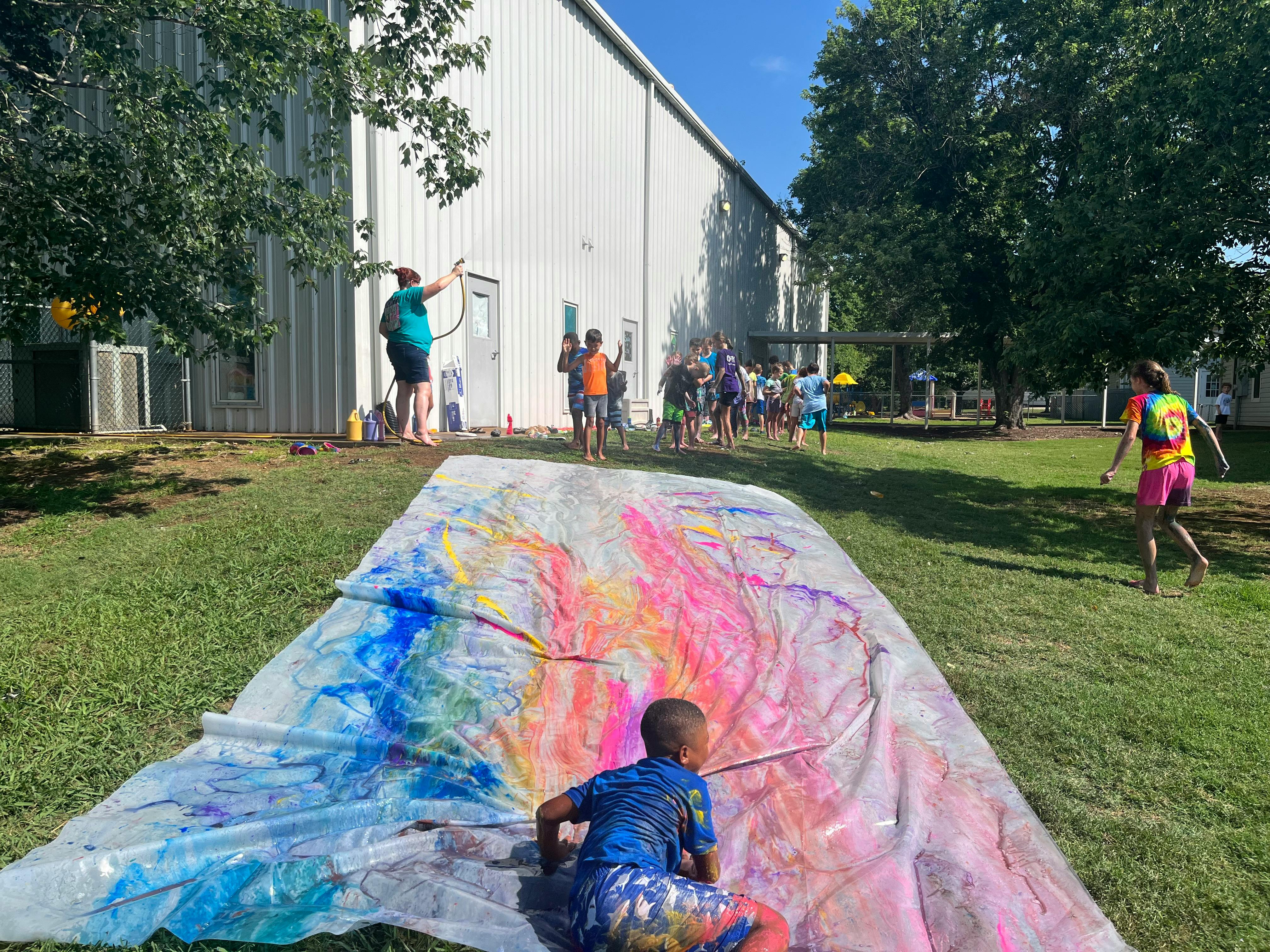 Child on a colorful slip and slide with people in the background