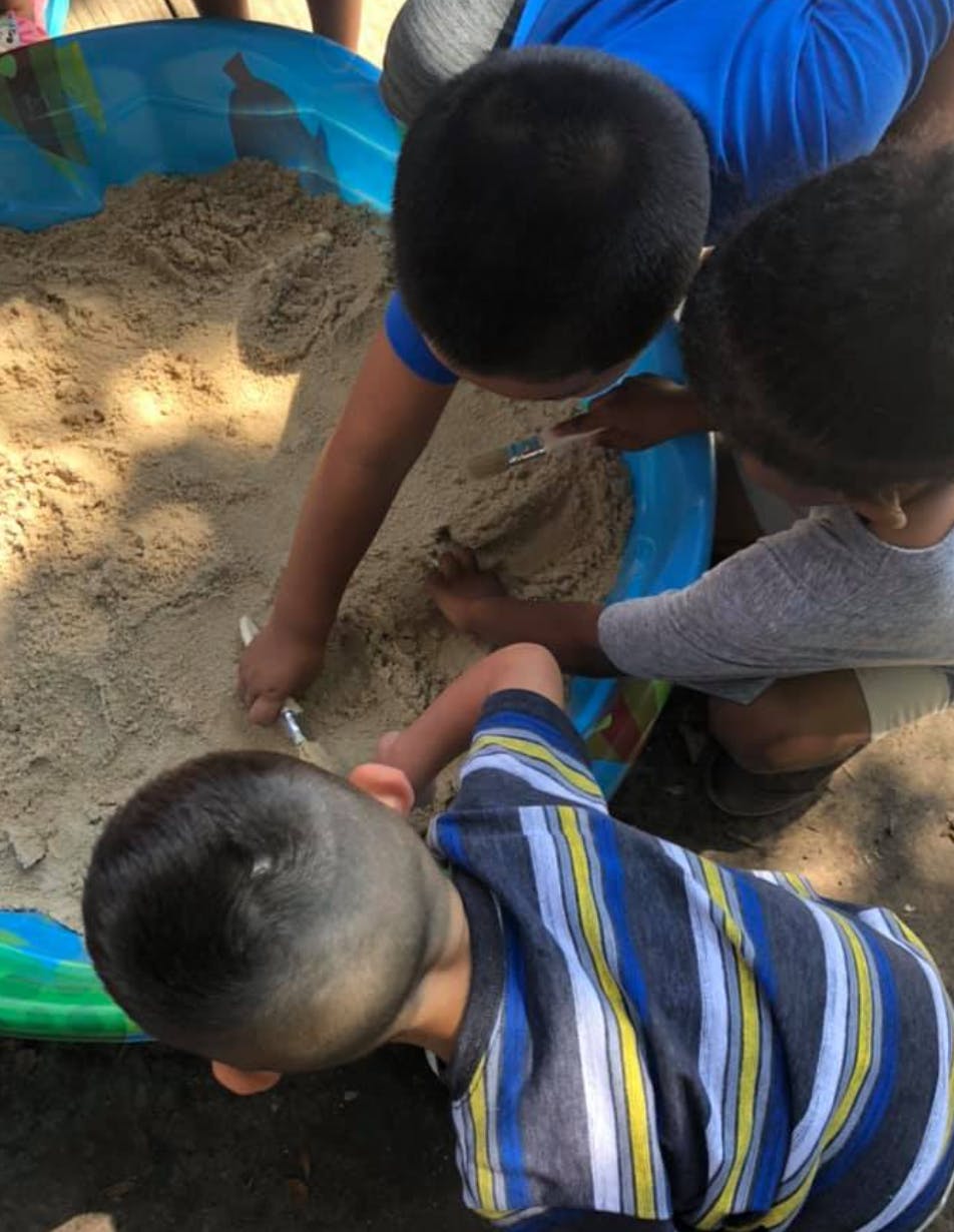 Three children playing in a sandbox