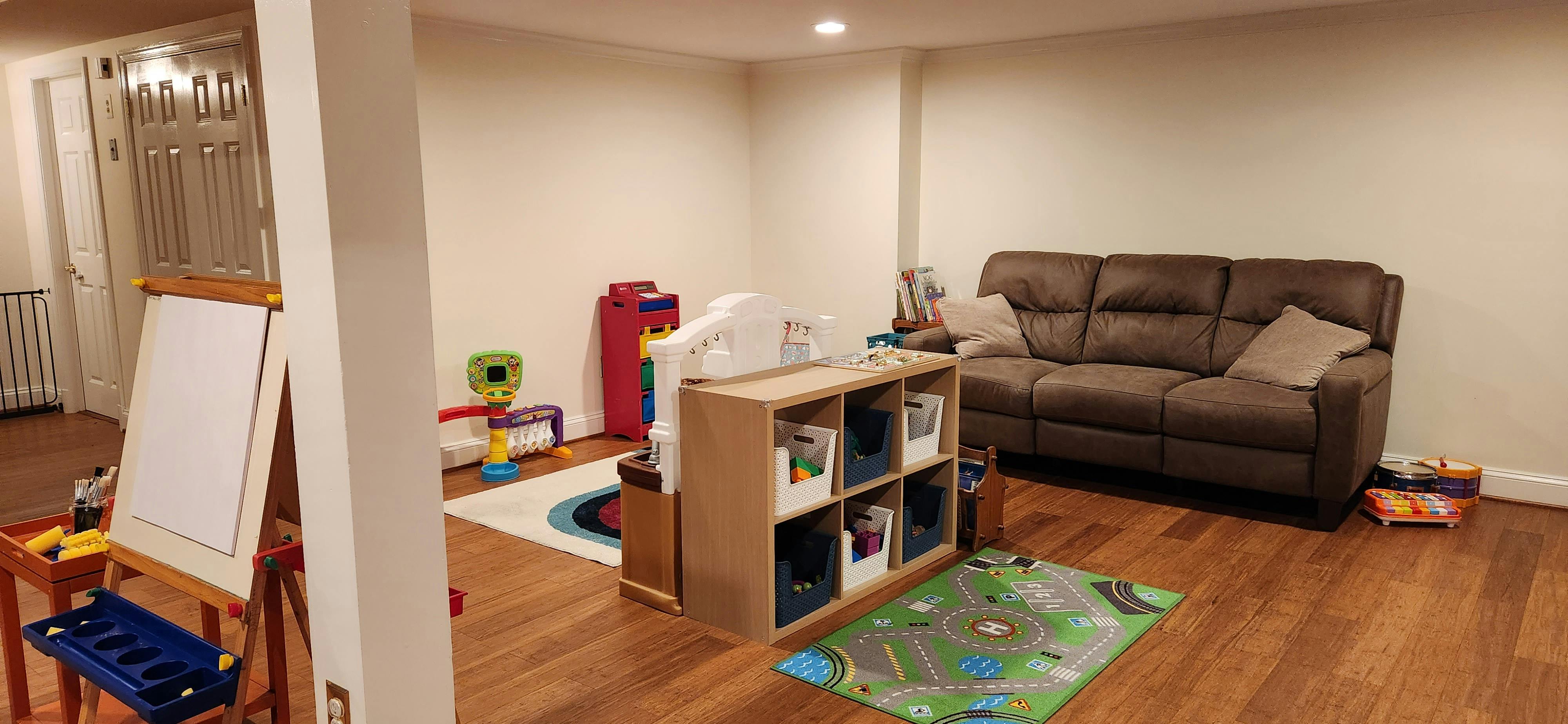 Living room with a brown sofa, storage unit, and children's play mats