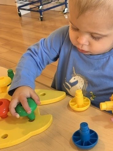 Child playing with colorful plastic toys on a wooden surface