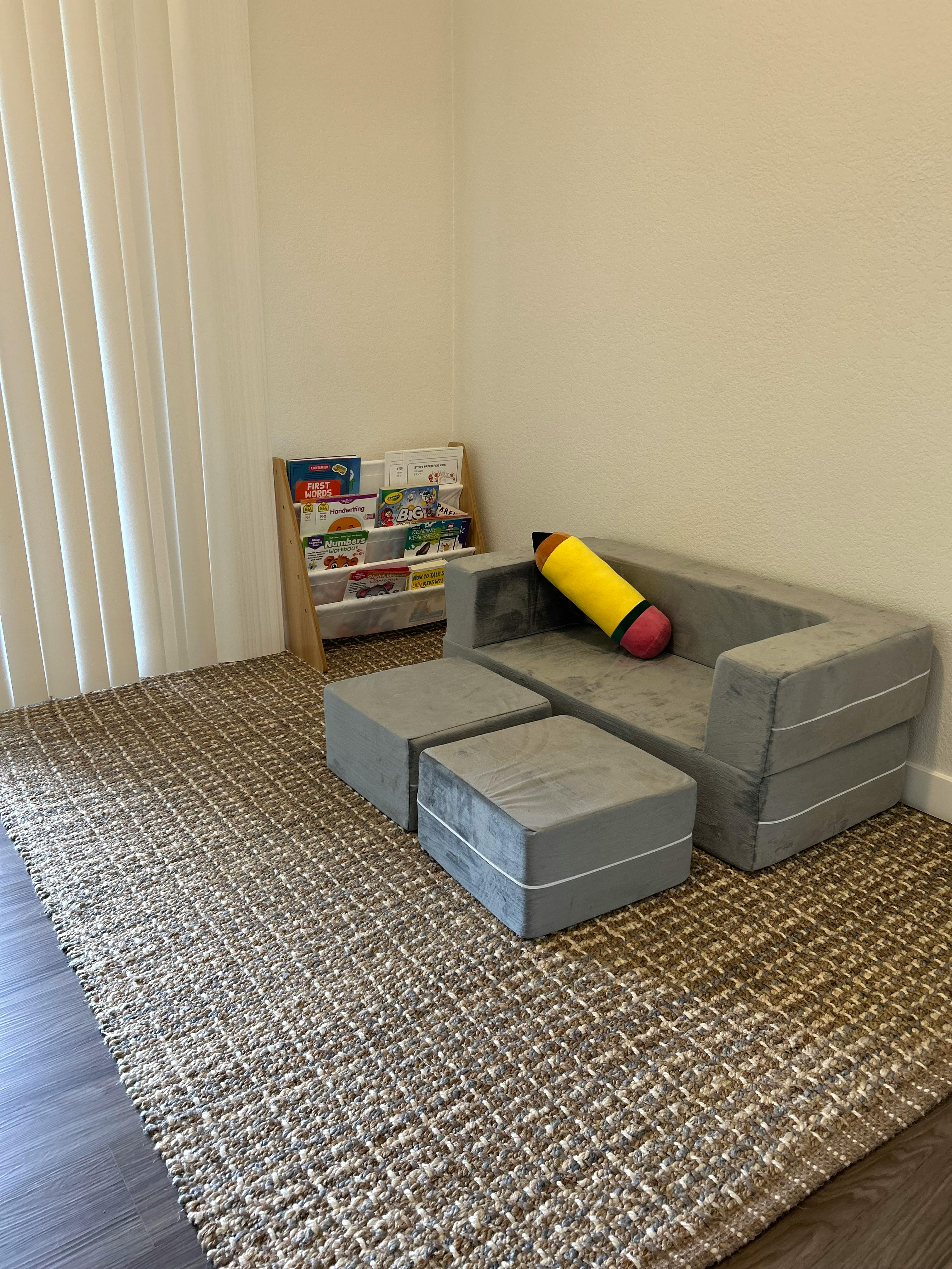 Kids' play area with a modular sofa, ottomans, and a book display
