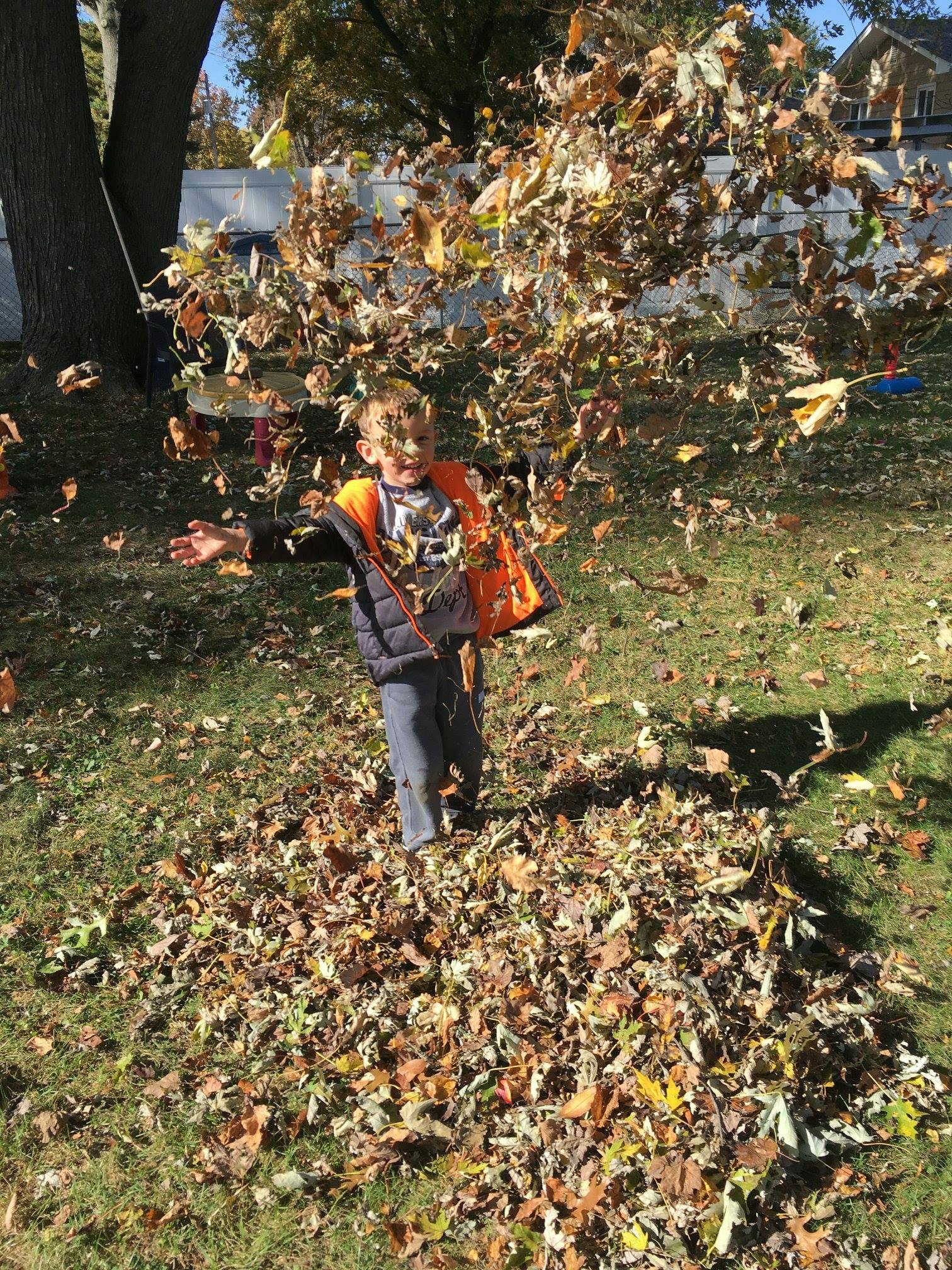 Child playing in a pile of autumn leaves