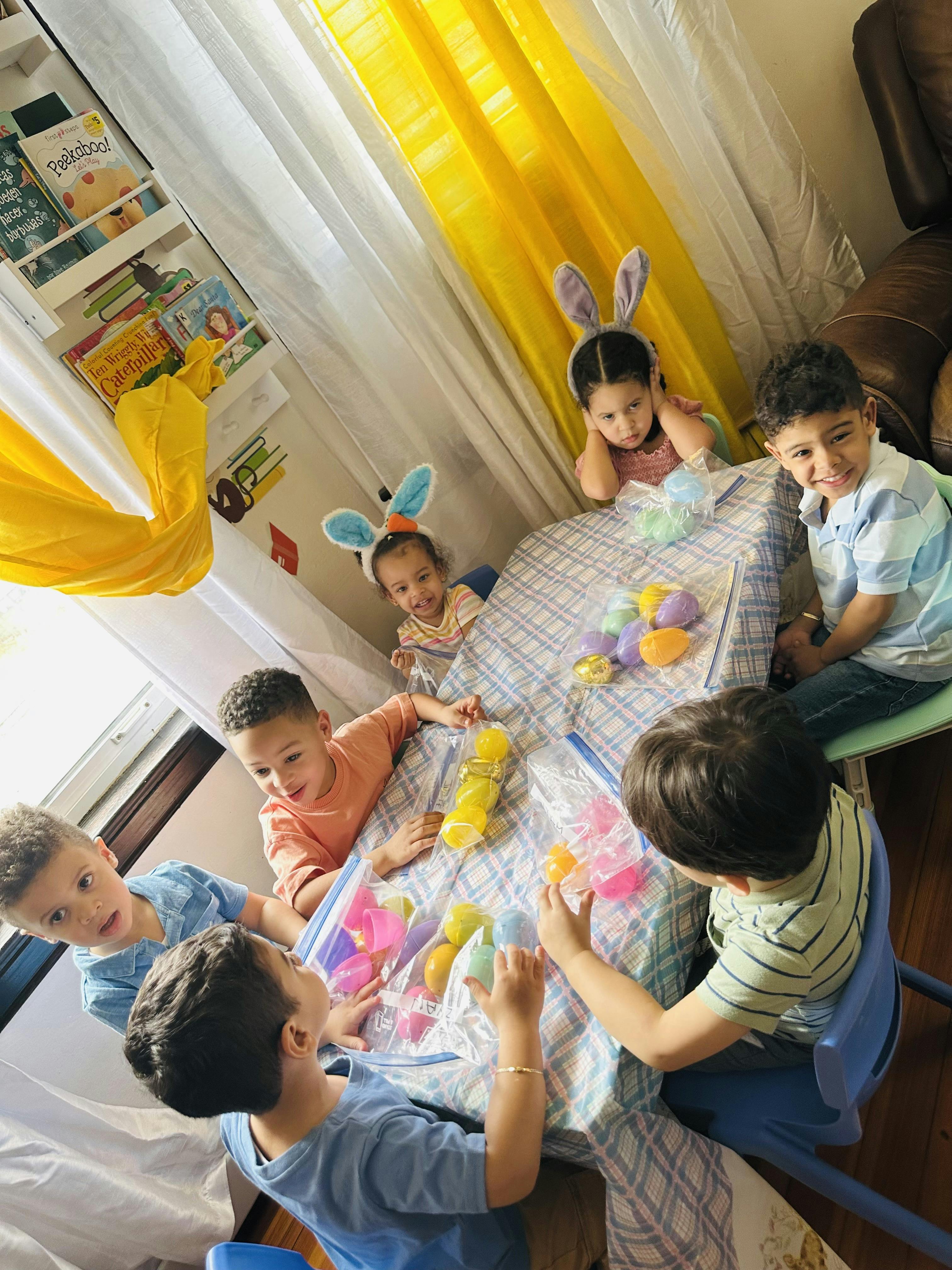 Group of children at a table sorting colorful plastic Easter eggs into bags