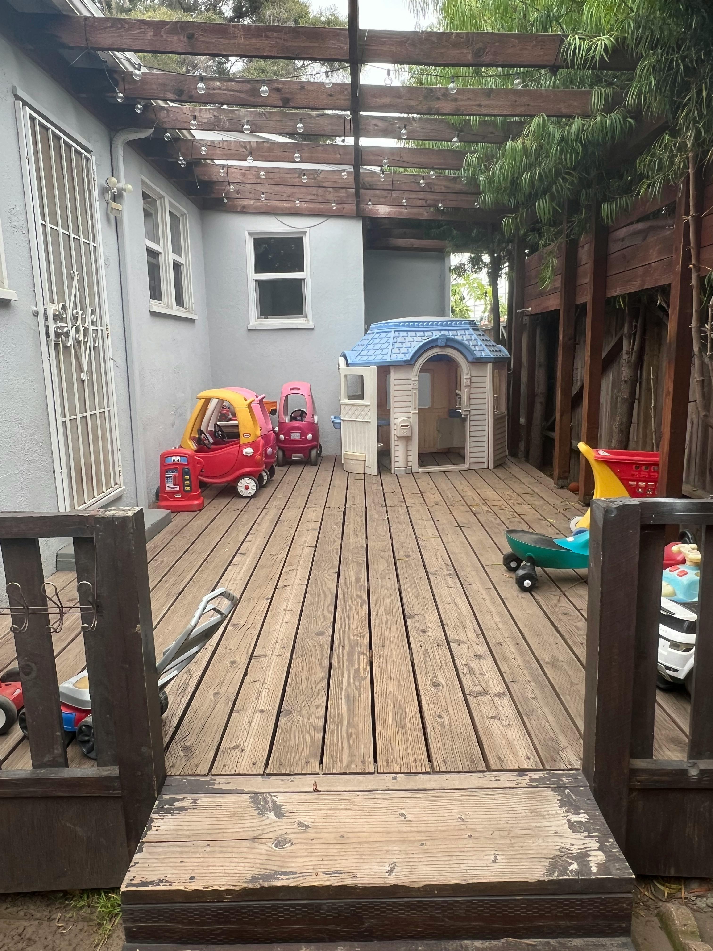 Outdoor wooden deck with children's toys and playhouse