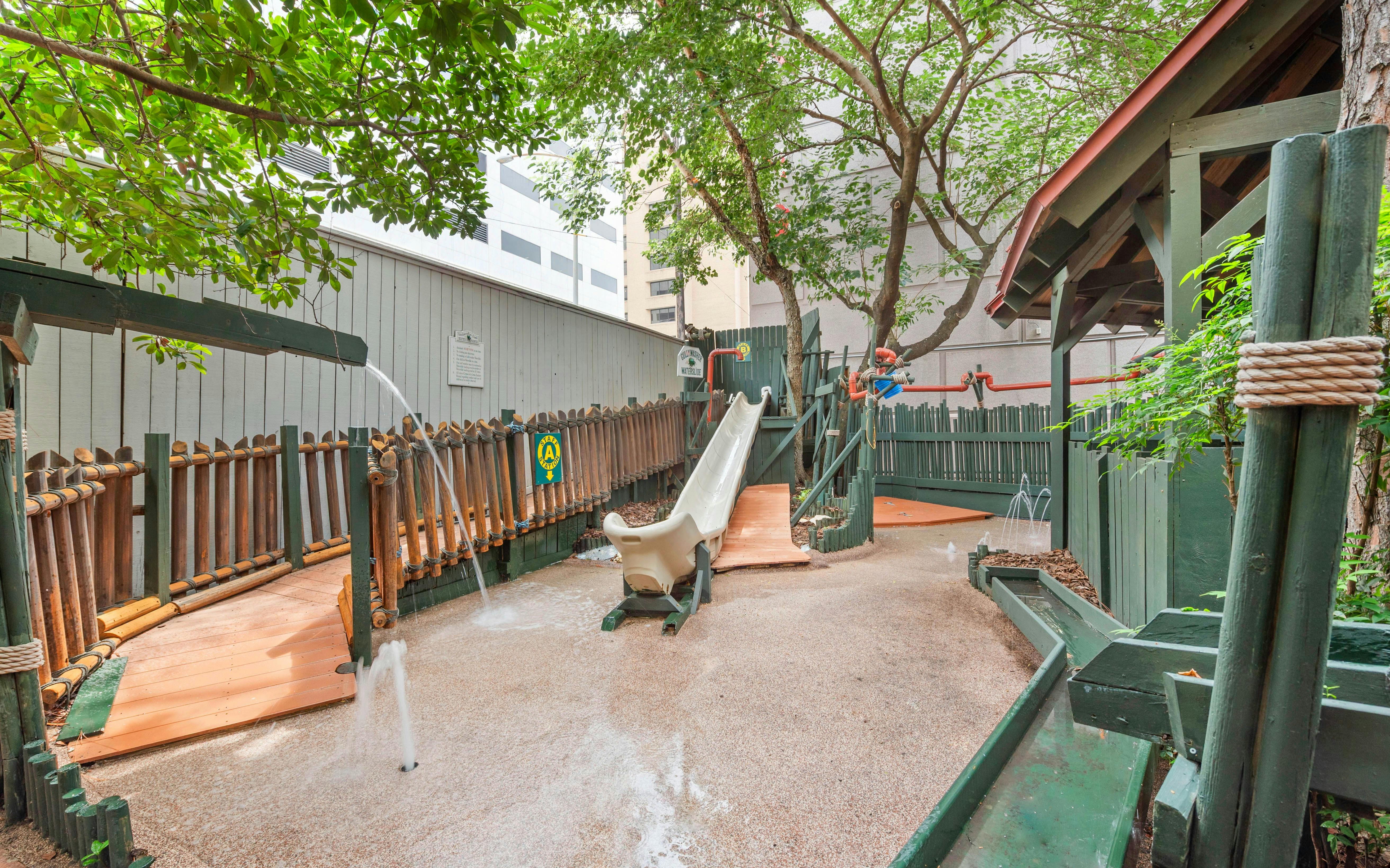 Water playground with a slide, fences, and water flowing into the play area