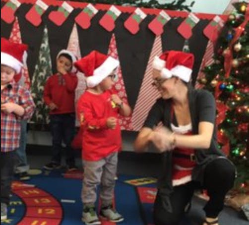 Adult and children wearing Santa hats in a classroom