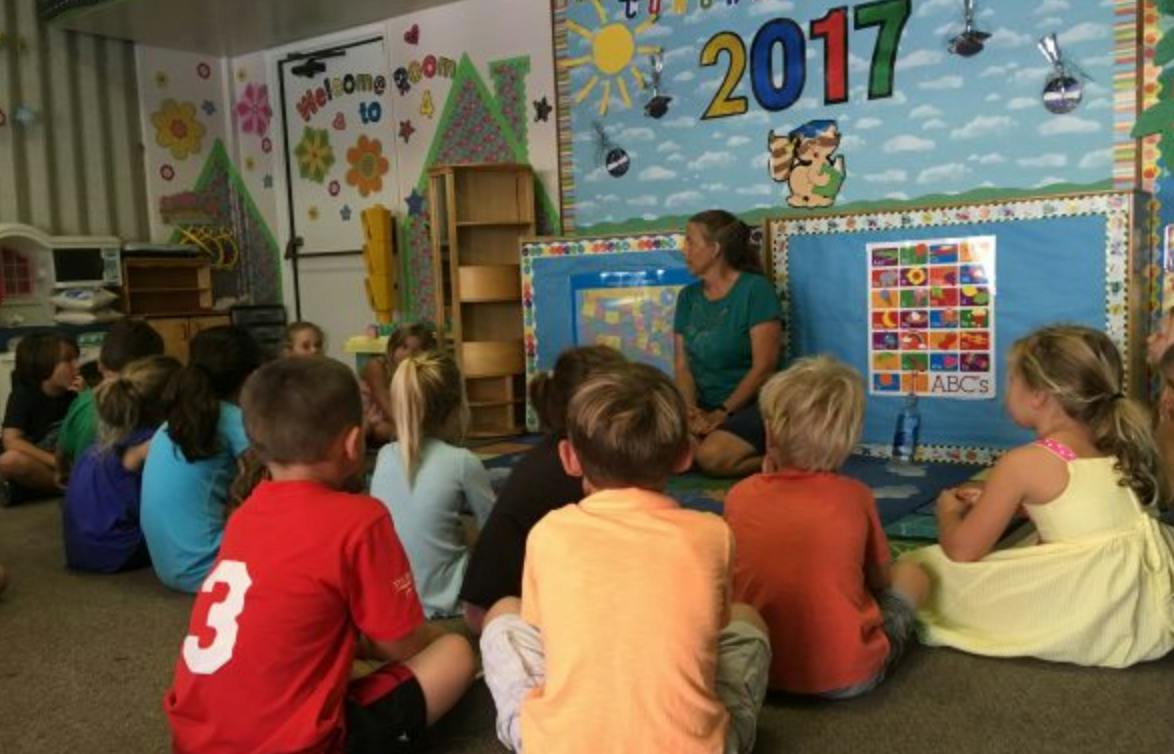 Adult and children sitting on the floor in a classroom
