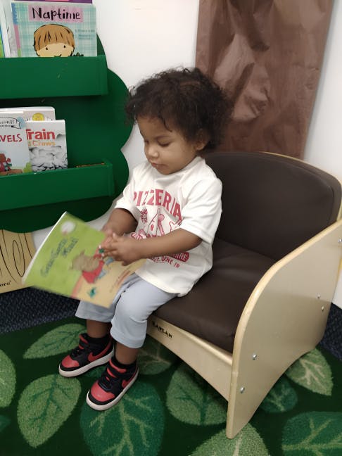 Child sitting in a small chair reading a book