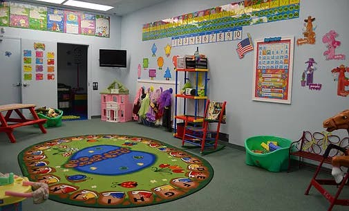 Colorful classroom with a round rug, small tables, and wall decorations