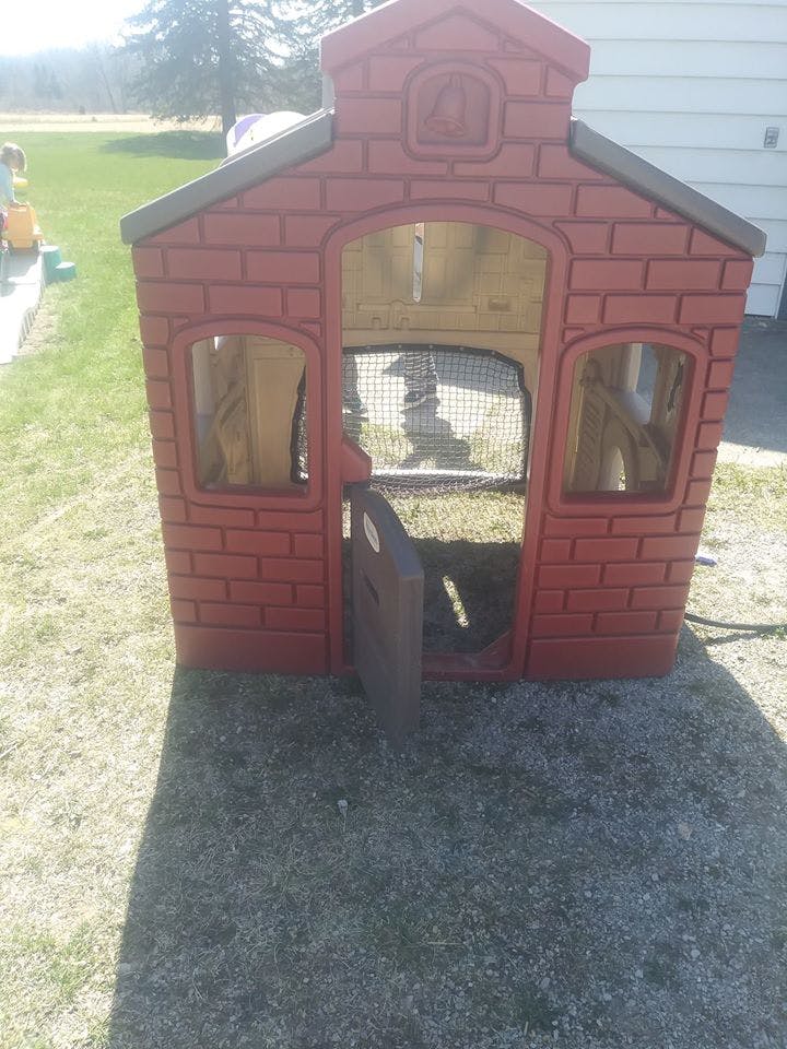 Red playhouse with an open door on grass