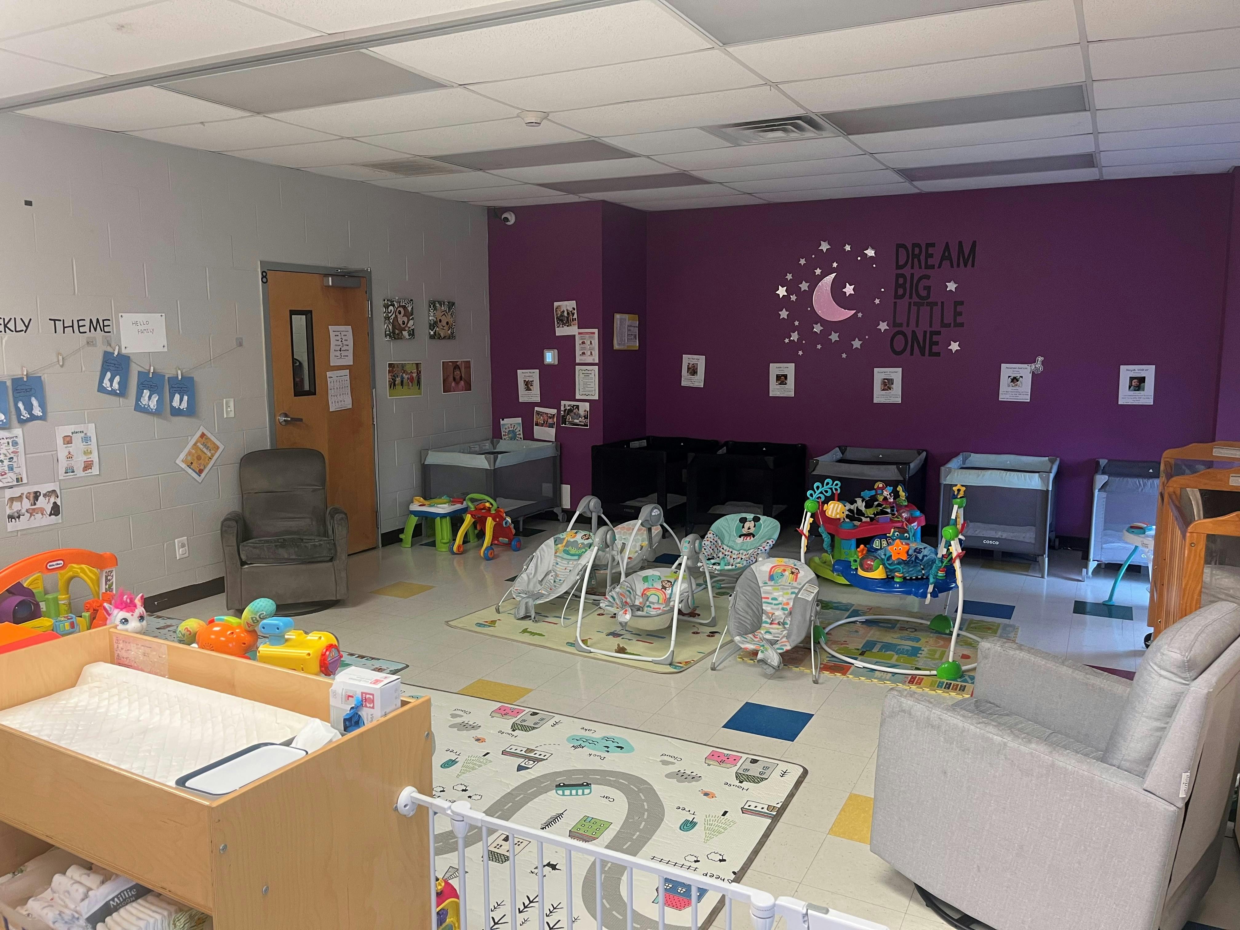 An empty nursery room with cribs, swings, and play mats
