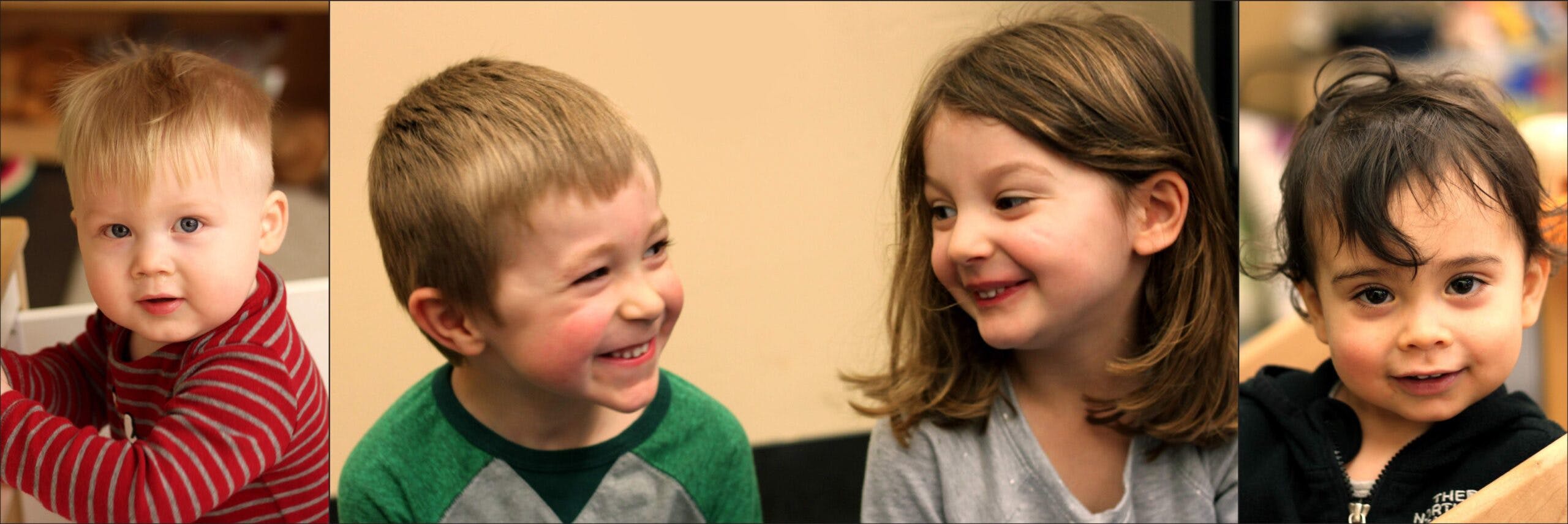 Four children smiling, one looking at the camera, two looking at each other