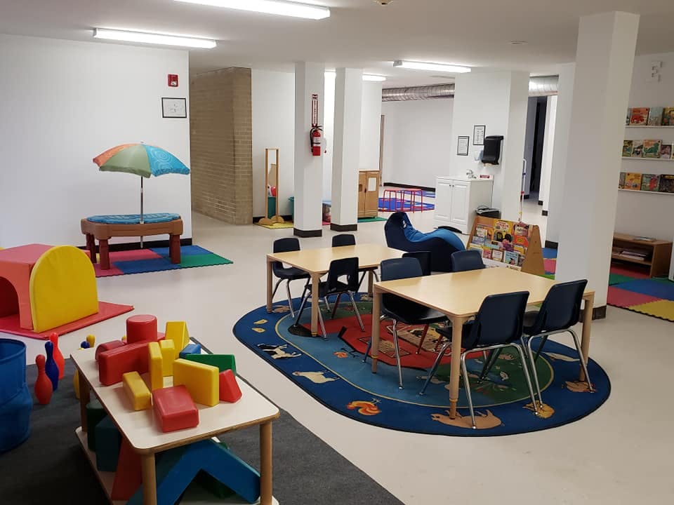 Playroom with tables, chairs, and colorful play equipment