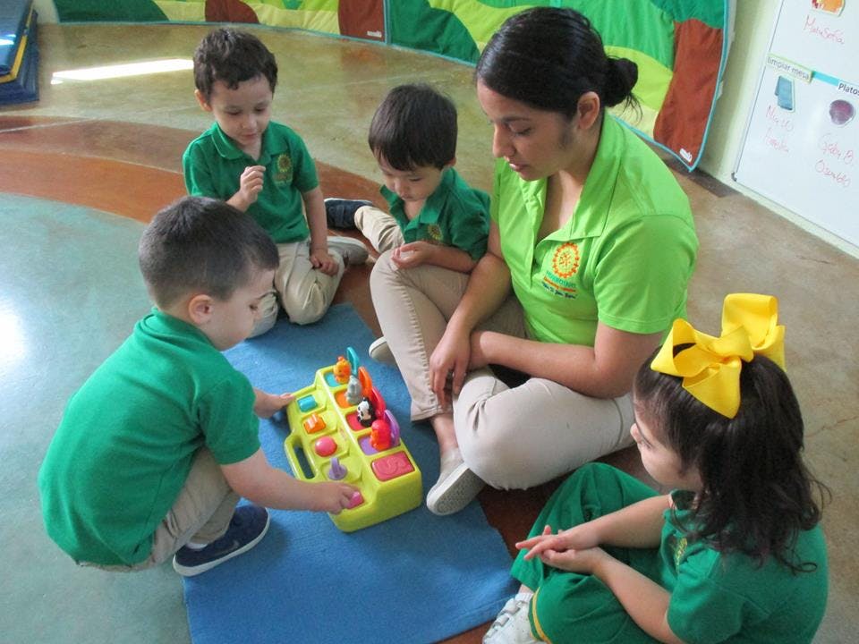 Adult and children playing with a toy in a classroom