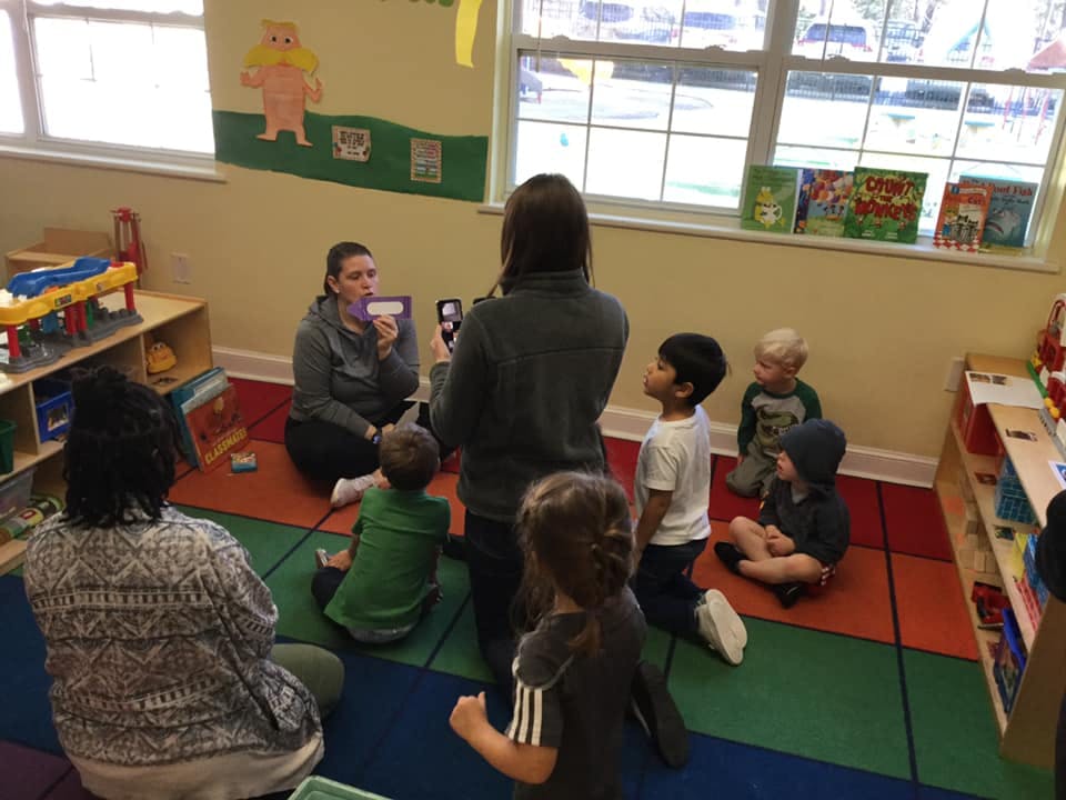 Adults and children sitting on the floor in a classroom