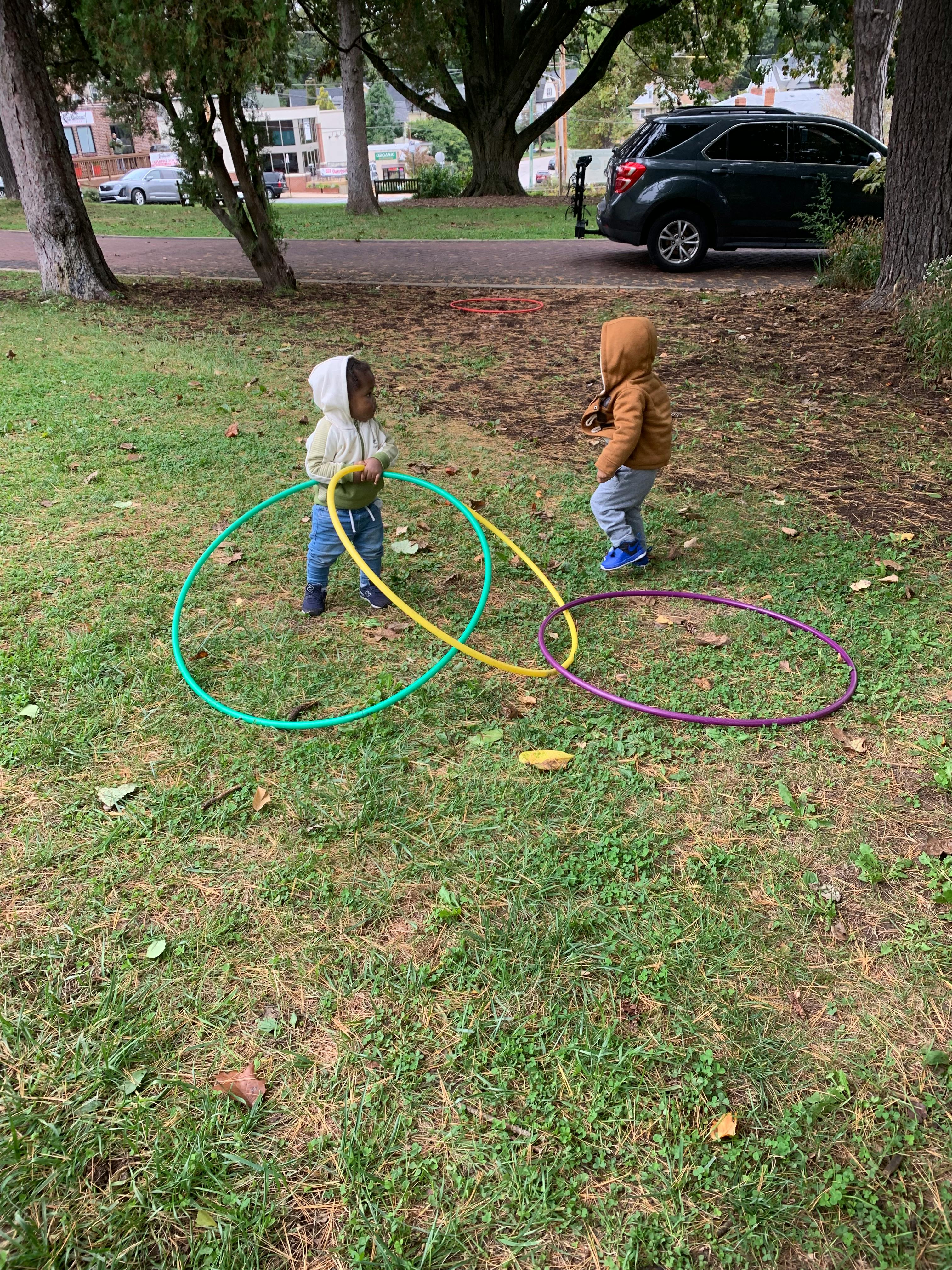 Two children playing with hula hoops on grass