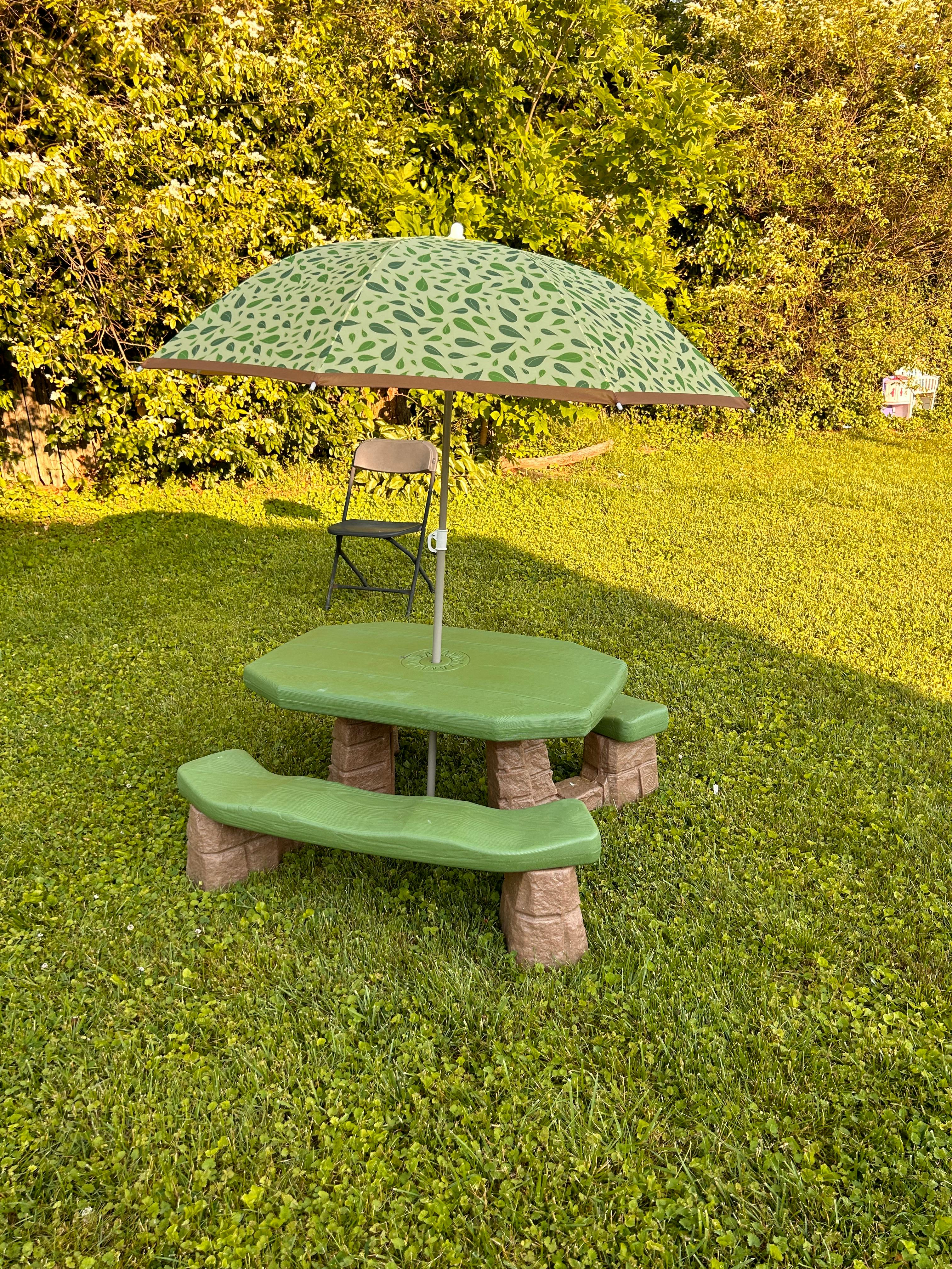 Green children's picnic table with an umbrella in a grassy area