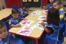 Children painting at a table in a classroom