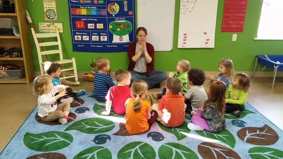 Adult and children sitting on a rug in a classroom