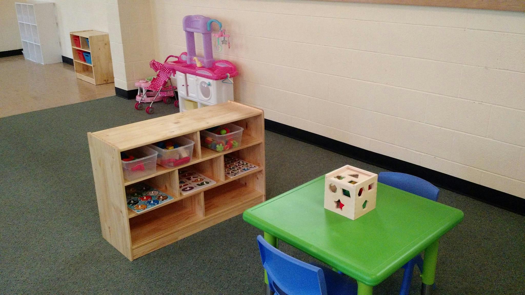 Classroom with toy shelf, play kitchen, and small table with block