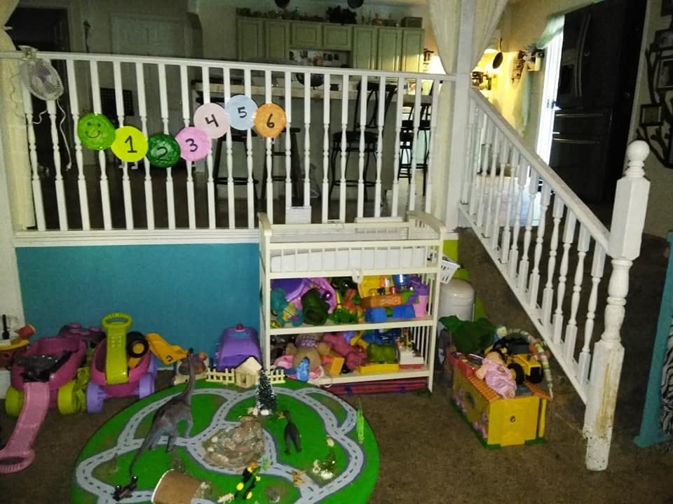 Play area with toys, a play mat, and a white railing with numbered circles
