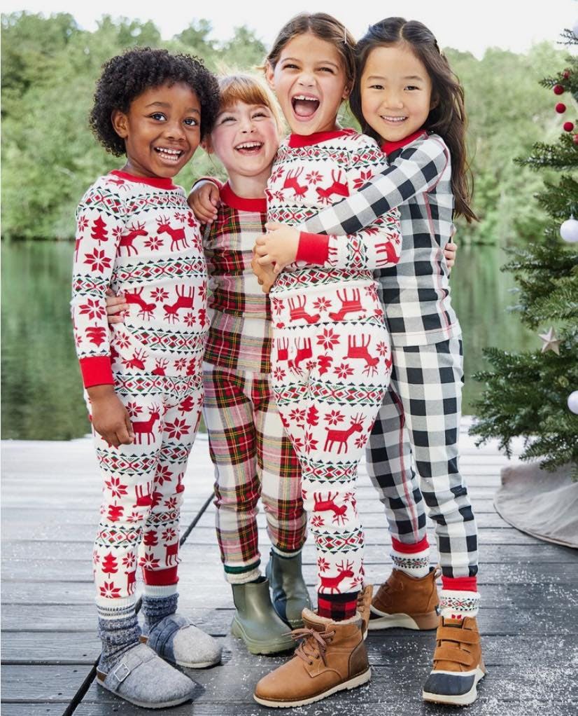 Four children in pajamas on a deck next to a lake and a body of water