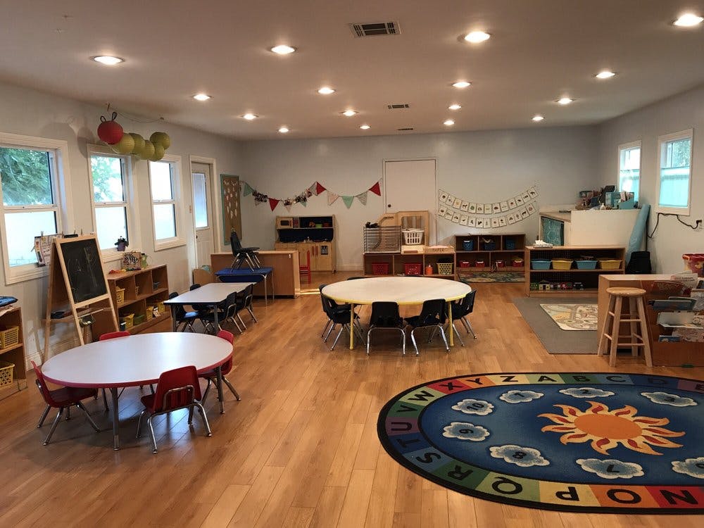 Classroom with tables, chairs, and a colorful rug