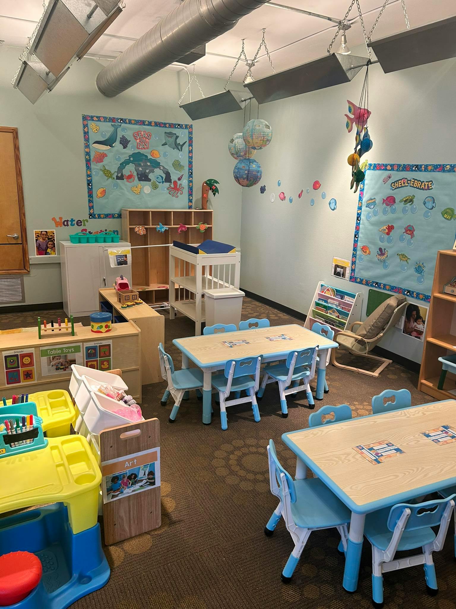 Classroom with small tables and chairs, marine-themed decorations, and storage units