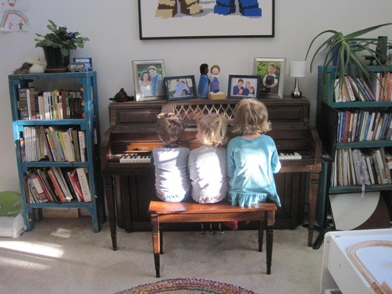 Three children sitting at a piano