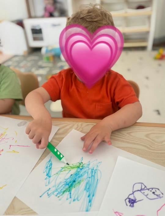 Child drawing with a marker on paper at a table