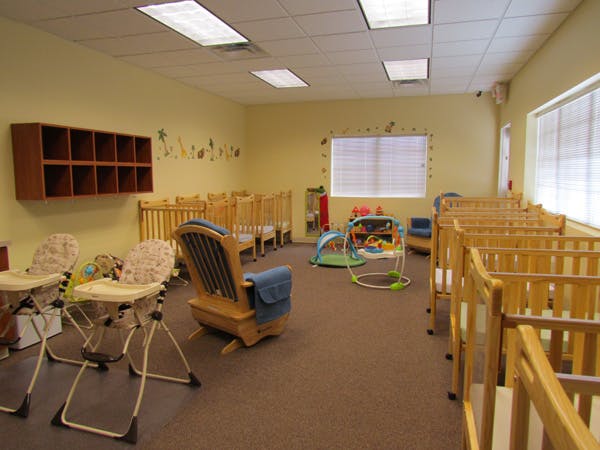 Room with multiple cribs, high chairs, and a rocking chair