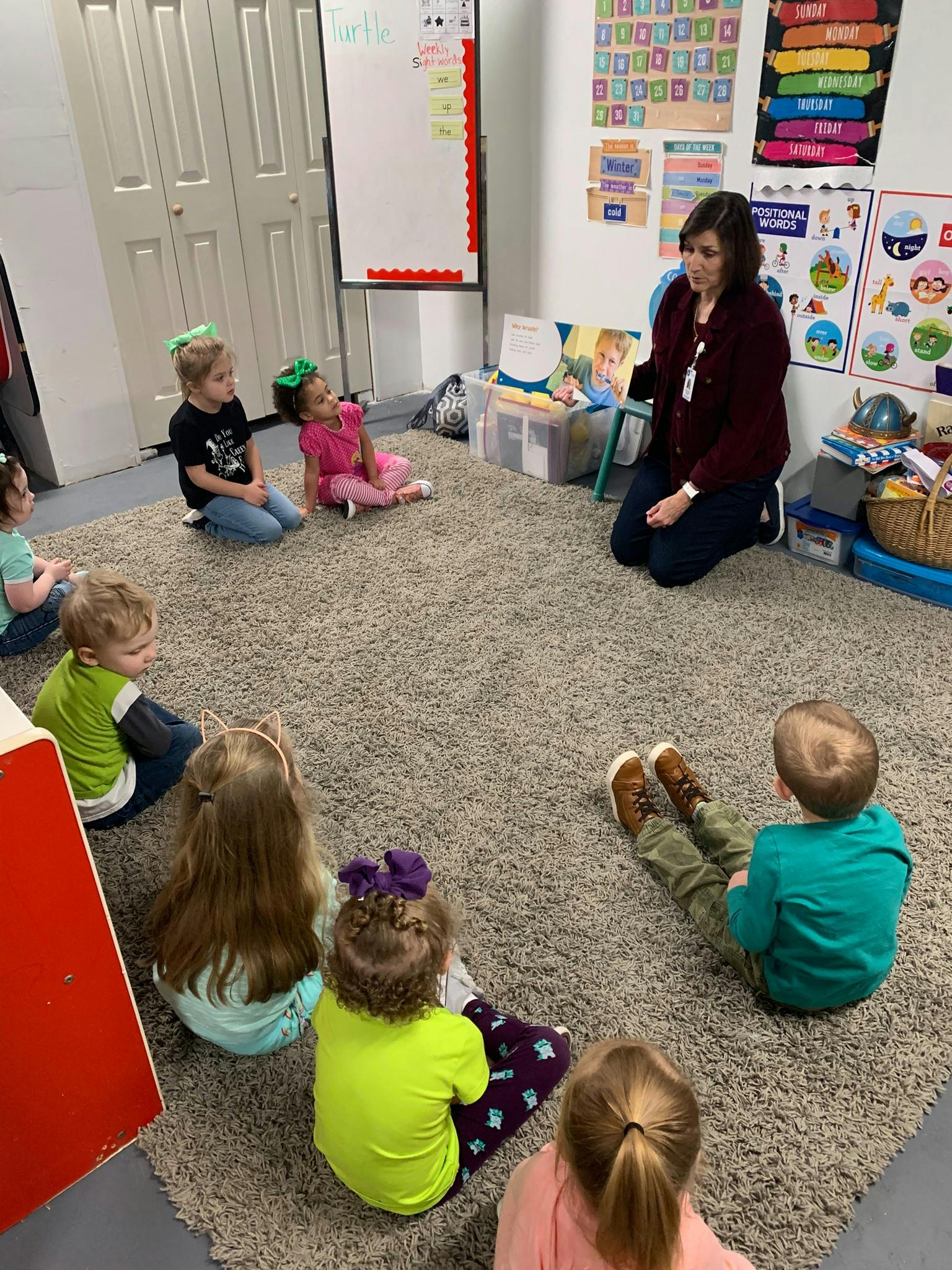 Adult and children sitting on a carpet in a classroom