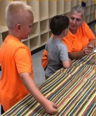 Adult and two children looking at striped fabric